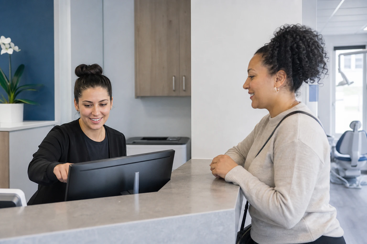 A dental receptionist helping a patient confirm an appointment at a modern clinic.